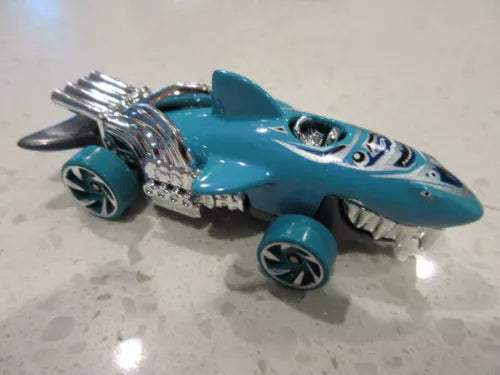 Blue shark-themed Hot Wheels die-cast toy race car with silver fins and open detail