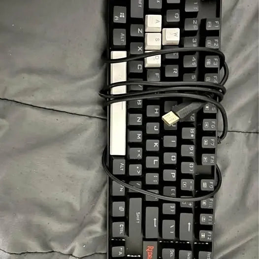Full-size keyboard with black keys and white spacebar, visible key layout and cable
