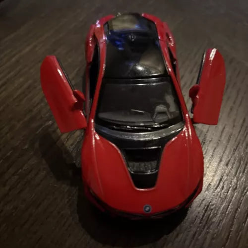 Red diecast sports car model with open doors, front view