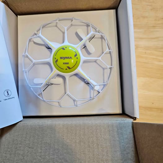 Small drone with circular protective frame and four propellers, green center hub