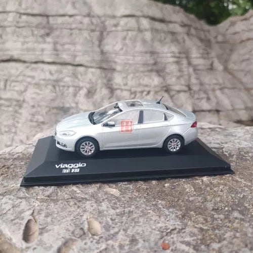 Silver diecast model sedan on black display base, side view, detailed wheels