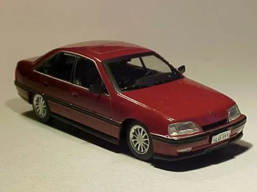 Red diecast sedan car model, front three-quarter view, loose 1/43 scale