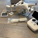 White quadcopter drone with remote controller and accessories, including tablet screen