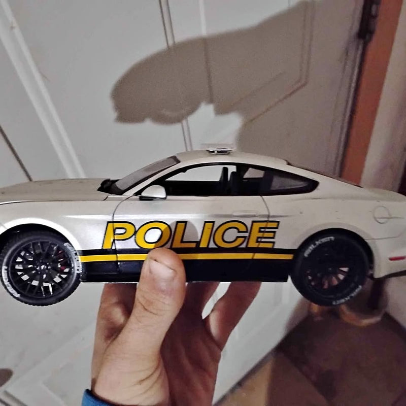 White diecast police car with yellow stripe and POLICE text, black wheels