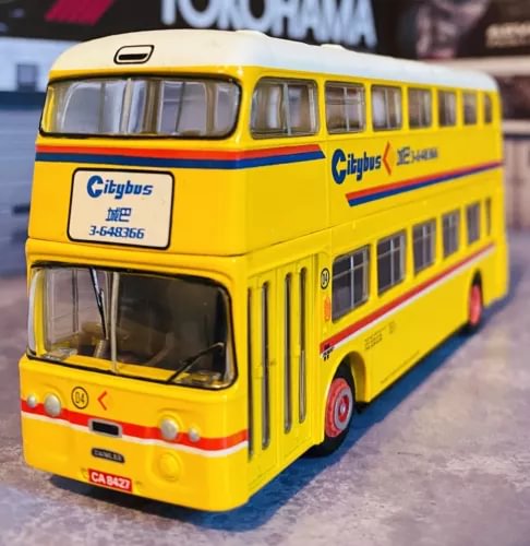 Yellow diecast city bus model with red stripe, front 3/4 view.