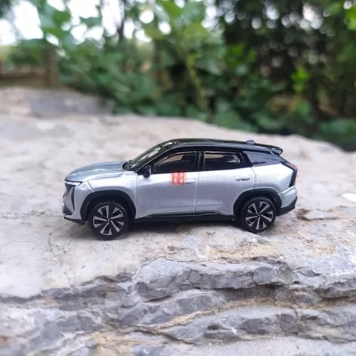 Silver diecast electric vehicle model with black wheels and tinted windows, side view