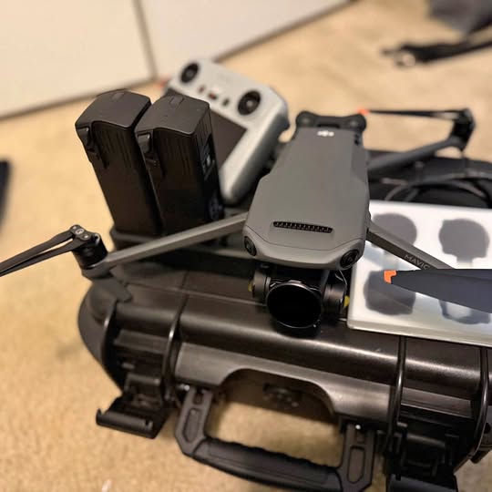 DJI drone with propellers and landing gear, gray body and mounted controller