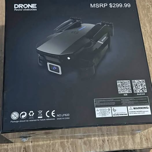 Foldable black drone with front camera module, shown on retail box