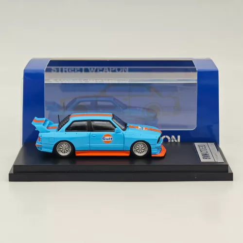Blue diecast BMW E30 M3 model car in clear display case on black base