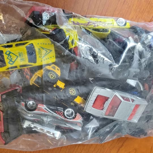 Assorted diecast car parts in clear plastic bag, yellow and red pieces