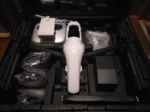 White aerial drone with controller and accessories in a hard case