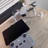 Foldable drone with gray body, propellers, and black controller with phone mount