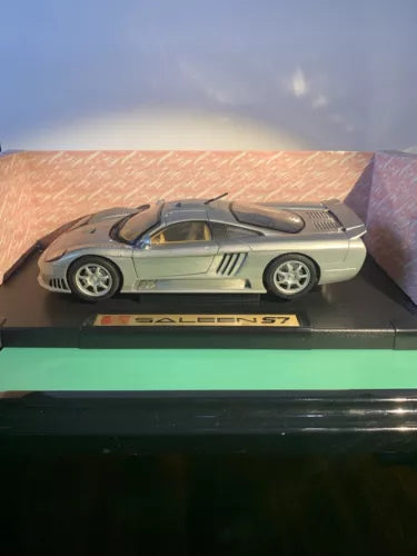Silver diecast coupe model car with tan interior, front side view on display base