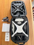 White quadcopter drone with camera in open hard case and accessory papers