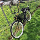 Black vintage bicycle with front wire basket and white tires behind a fence