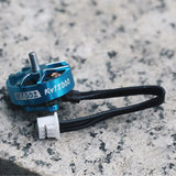 Blue FPV brushless drone motor with M1002 KV18000 label, metal shaft, and wire leads