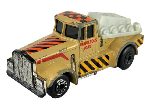 Vintage diecast semi truck with yellow cab and barrel, orange hazard stripes