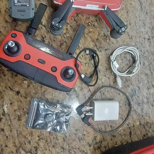 DJI Spark drone with red body, propeller arms, and accessories cable