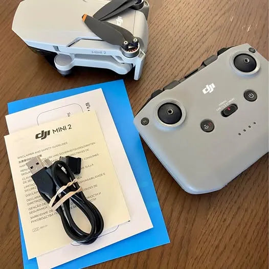 Light gray DJI Mini 2 drone with controller and charging cable on paper manual