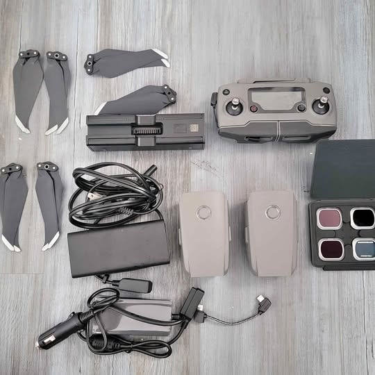 Drone accessories bundle: propellers, batteries, charger cables, and controller remote.