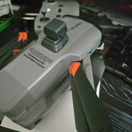 White drone with dark gray body and orange accents, top view with control module.