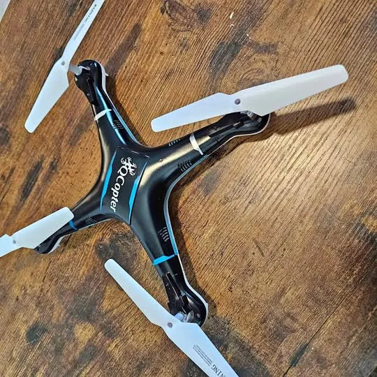 QCopter QC1 quadcopter drone, black with blue accents and four white propellers
