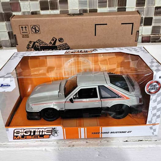 Gray and black 1:24 diecast car model with red stripe, in display box tray