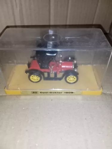 Vintage diecast toy car with red body and yellow wheels in clear display case
