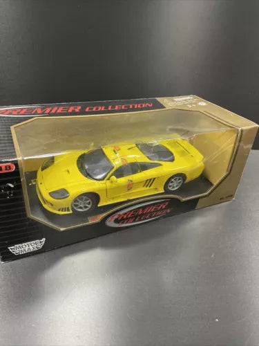 Yellow diecast model car in display box with clear window, front three-quarter view.