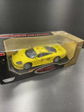 Yellow diecast model car in display box with clear window, front three-quarter view.