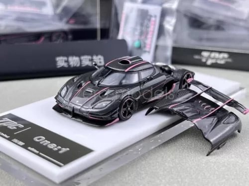 Diecast racing model car with black carbon body and pink accents, front 3/4 view
