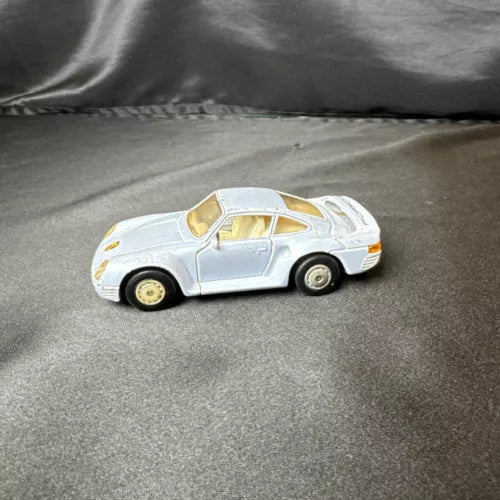 White diecast toy car, Porsche 959 MC, 1:36 scale with gold details and side view