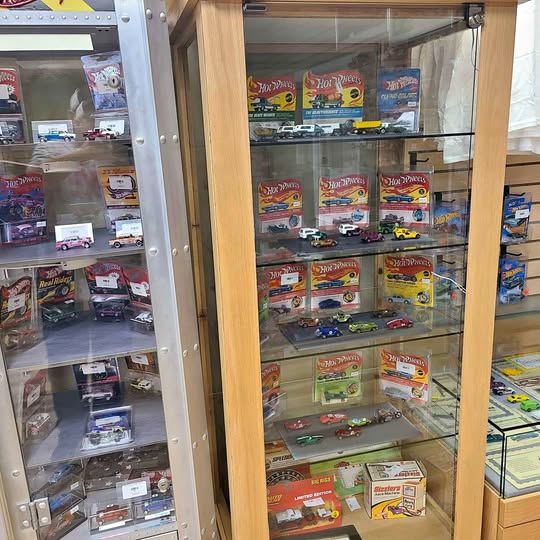 Glass display cabinet with diecast car toy packs on shelves