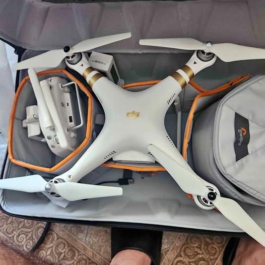 White quadcopter drone with four propellers and landing legs, in carrying case