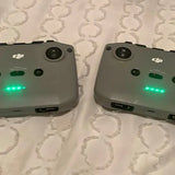 DJI Mini 2 drone controllers, two gray controllers with green LED indicators