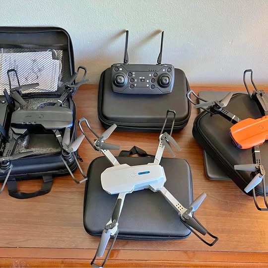 Foldable quadcopter drone with controller and propeller guards, white and dark body