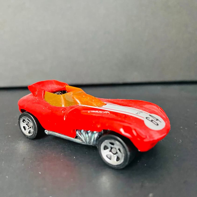 Red diecast toy car with gray wheels and orange/yellow top