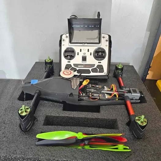 Quadcopter drone with remote controller and green propellers on table