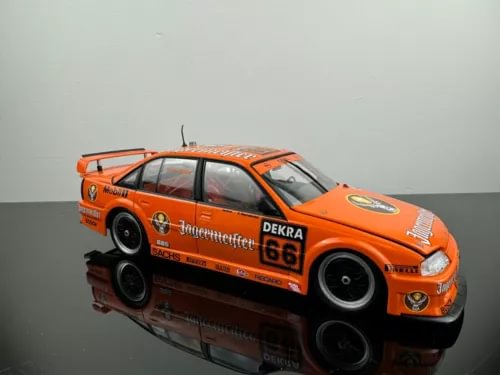 Orange diecast race car model with front headlights and number 68 on doors