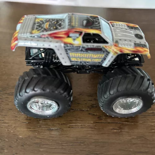 Gray diecast monster truck with oversized black tires and flame graphics, 1:64 scale