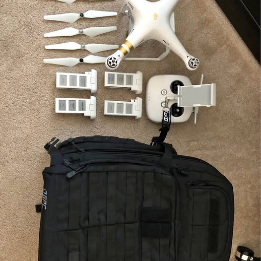 White quadcopter drone with propellers, controller, and black carry bag