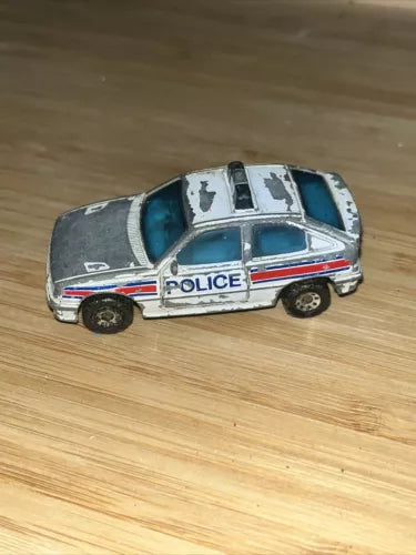 Diecast police car toy with teal hood and white roof, silver body and blue stripe