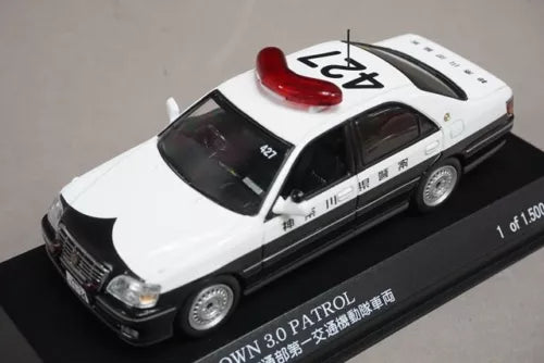 Silver metallic diecast sedan model car with black grille and red roof beacon
