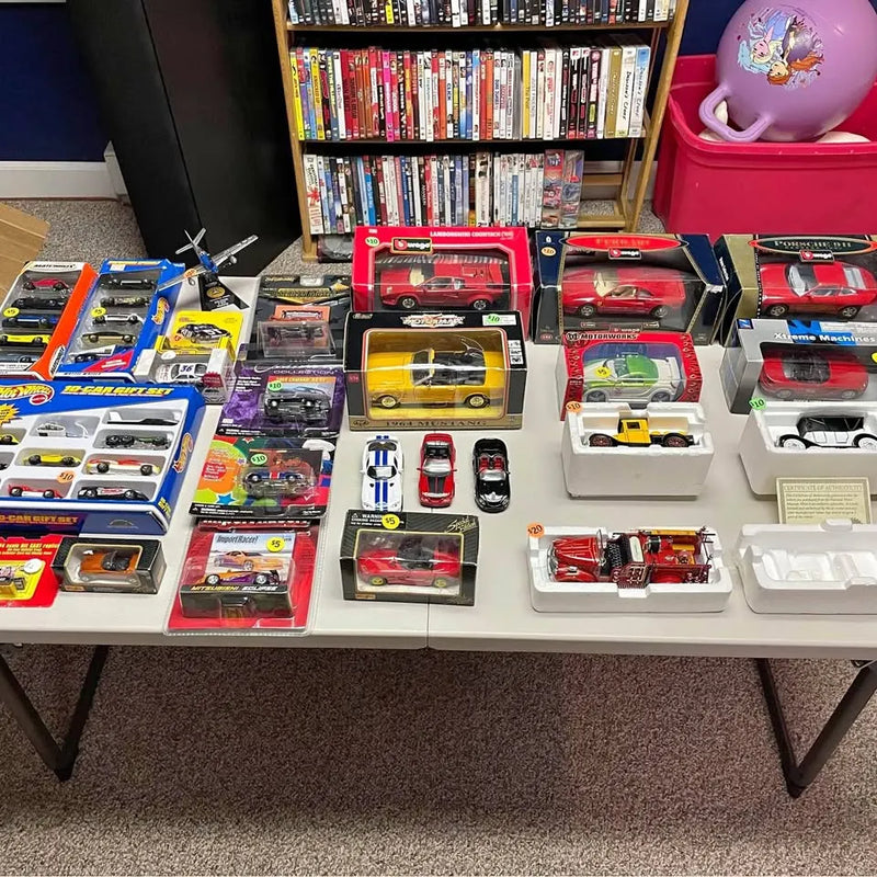 Assorted diecast cars in blister and box packaging on display tray