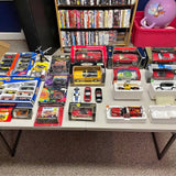 Assorted diecast cars in blister and box packaging on display tray