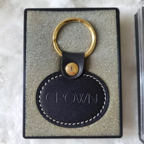 Leather keychain tag with round metal snap and gold-tone keyring in gift box