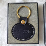 Leather keychain tag with round metal snap and gold-tone keyring in gift box