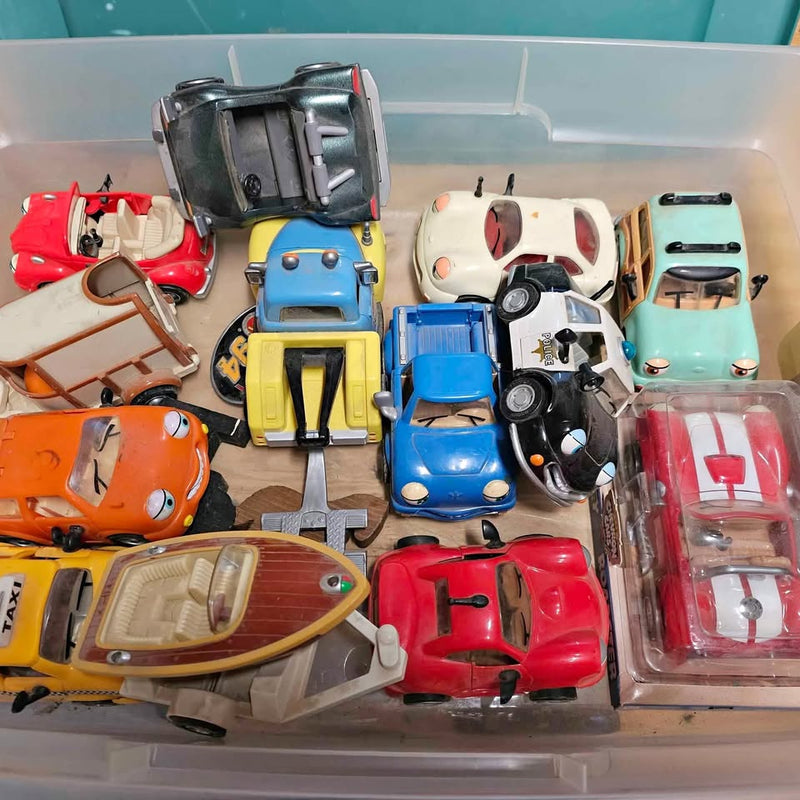 Assorted diecast toy cars in a clear plastic bin, red, blue, yellow and white
