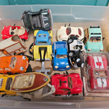 Assorted diecast toy cars in a clear plastic bin, red, blue, yellow and white
