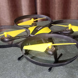 Yellow and black quadcopter drone with four spinning propellers and landing legs